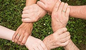 Team - Das Bild zeigt Hände, welche sich gegenseitig festhalten und so einen Kreis bilden.